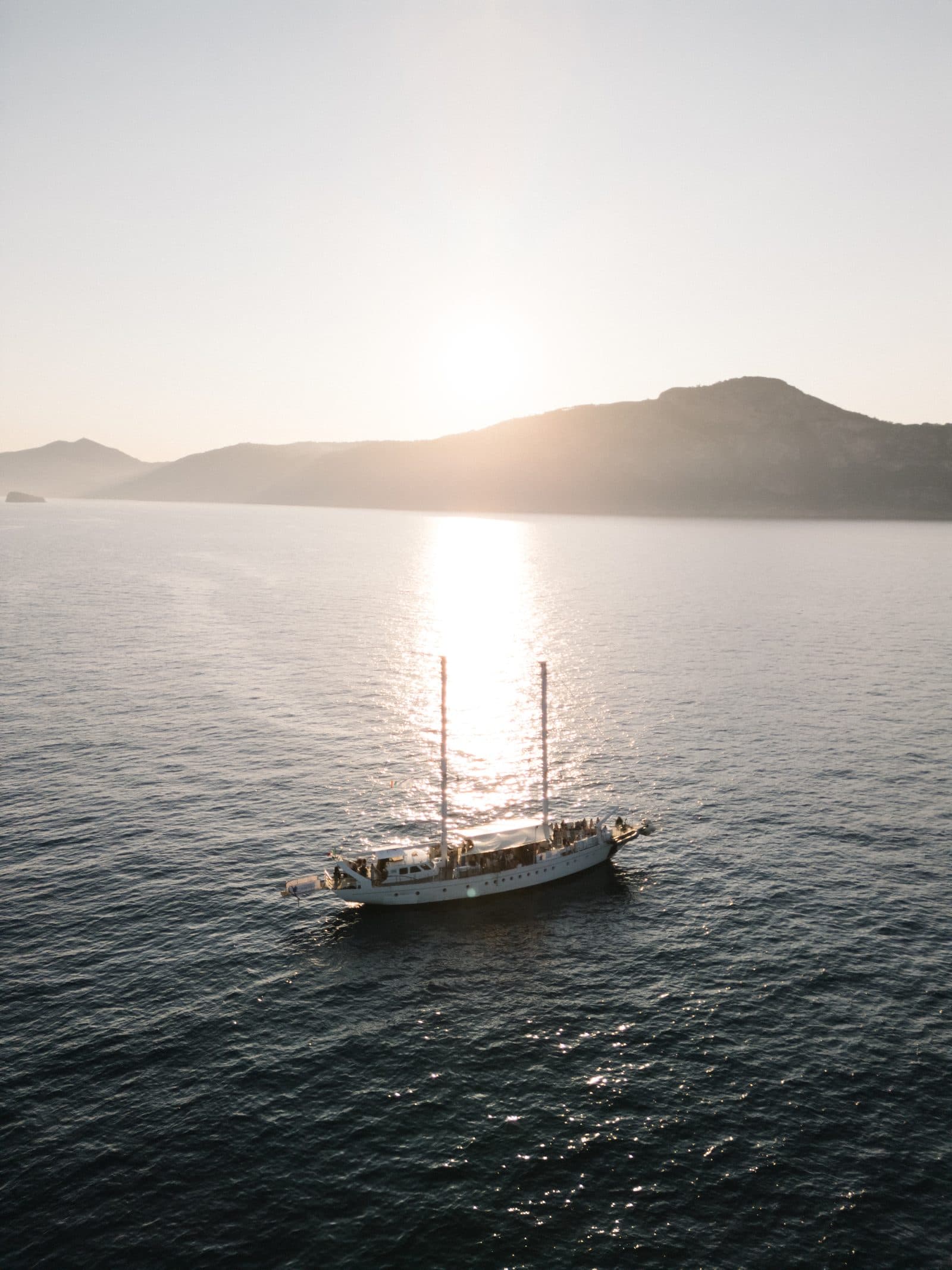 Sailing boat seen from above in the deep blue water off the coast