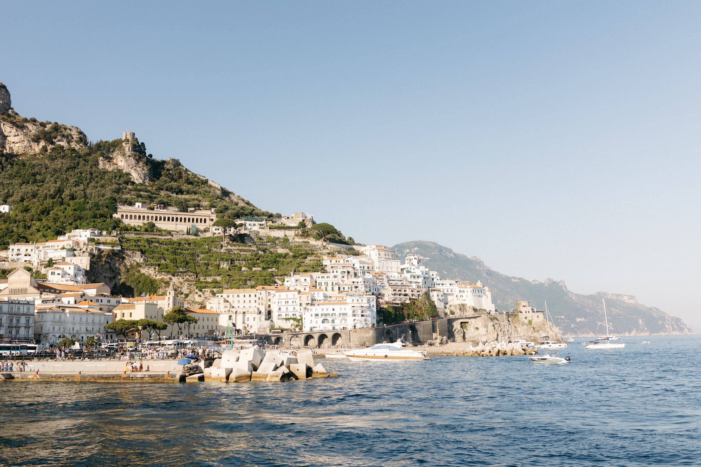 Amalfi seen from the sea, houses stacked on the cliff above the harbour
